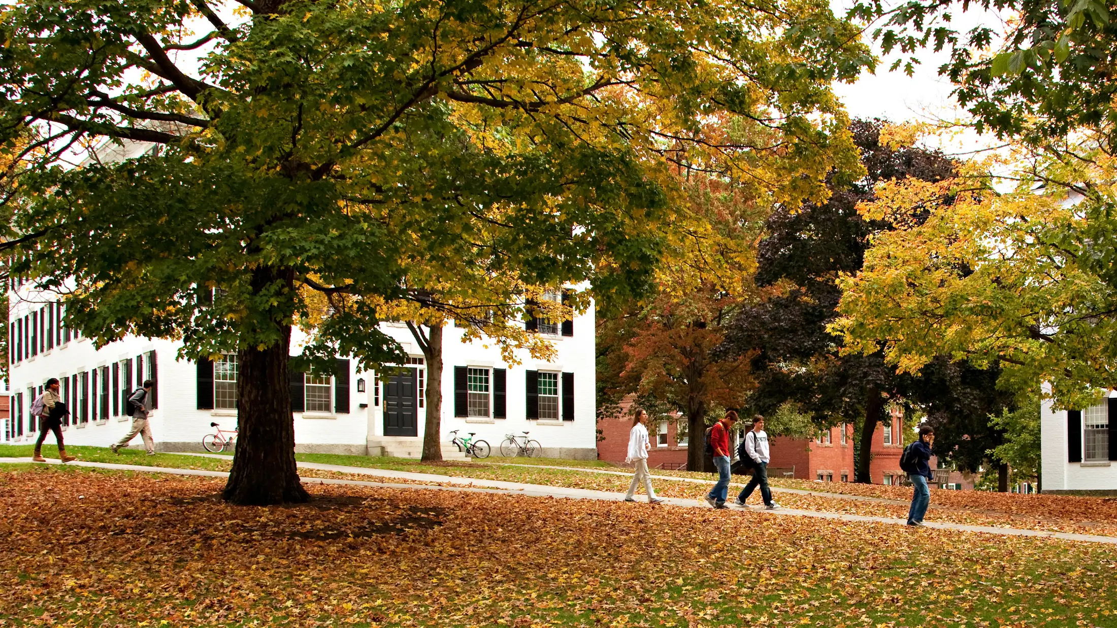 Dartmouth students walking to classes among fall leaves on the Big Green in Hanover, New Hampshire.
