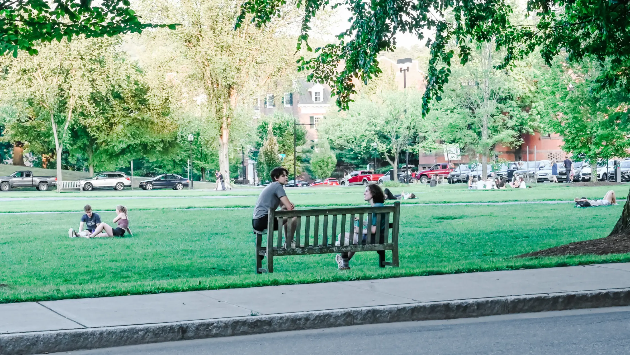 Students enjoy a summer day under shady trees on Dartmouth Green.